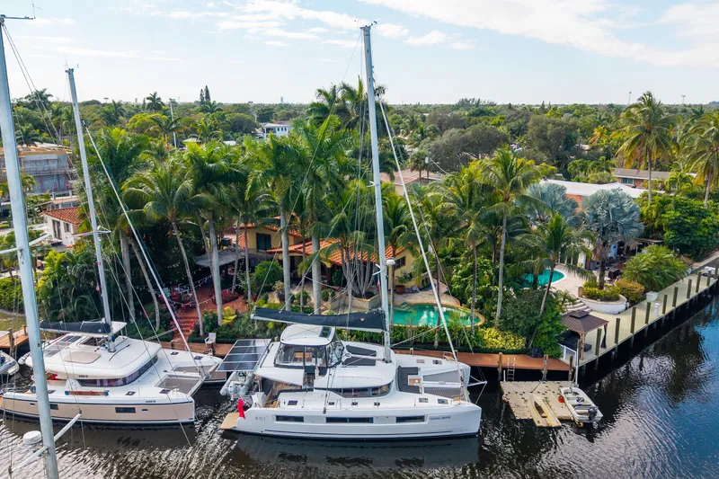 Going Deeper Yacht Photos Pics 2024 Lagoon 51 catamaran docked by tropical waterfront property with lush greenery.