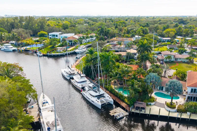Going Deeper Yacht Photos Pics Aerial view of Lagoon 51 yacht, 2024 model, docked in a lush, residential canal setting.