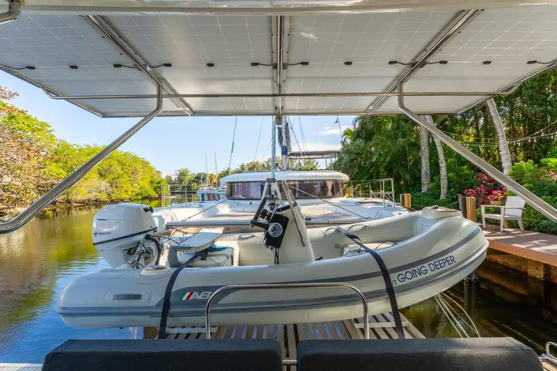 Going Deeper Yacht Photos Pics 2024 Lagoon 51 yacht with dinghy, docked in a lush, tropical setting.