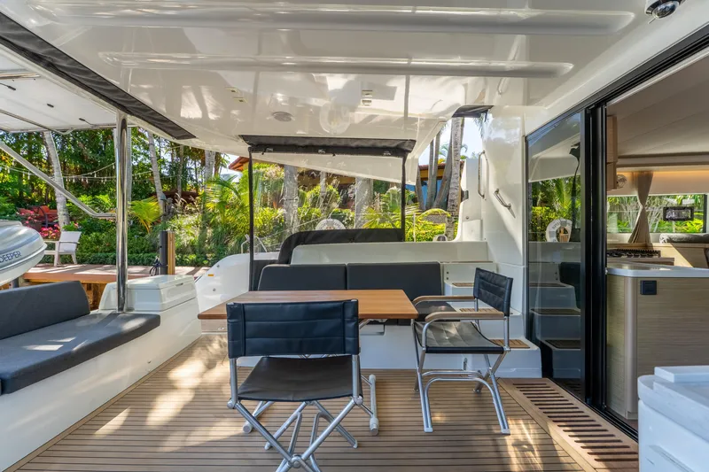Going Deeper Yacht Photos Pics Luxurious 2024 Lagoon 51 yacht interior with seating, table, and open sliding doors.