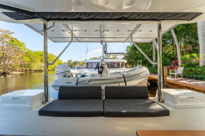 Going Deeper Yacht Photos Pics 2024 Lagoon 51 yacht interior with seating, docked near lush greenery.