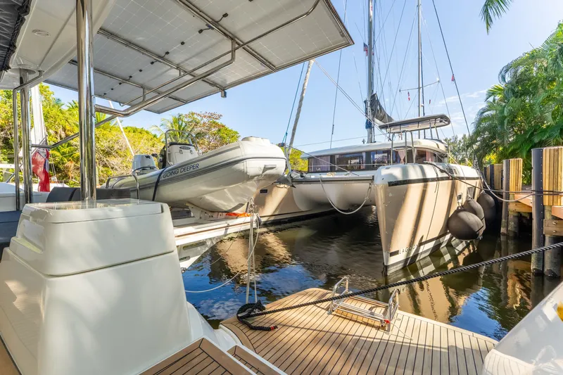 Going Deeper Yacht Photos Pics 2024 Lagoon 51 catamaran docked with tender boat, surrounded by lush greenery.