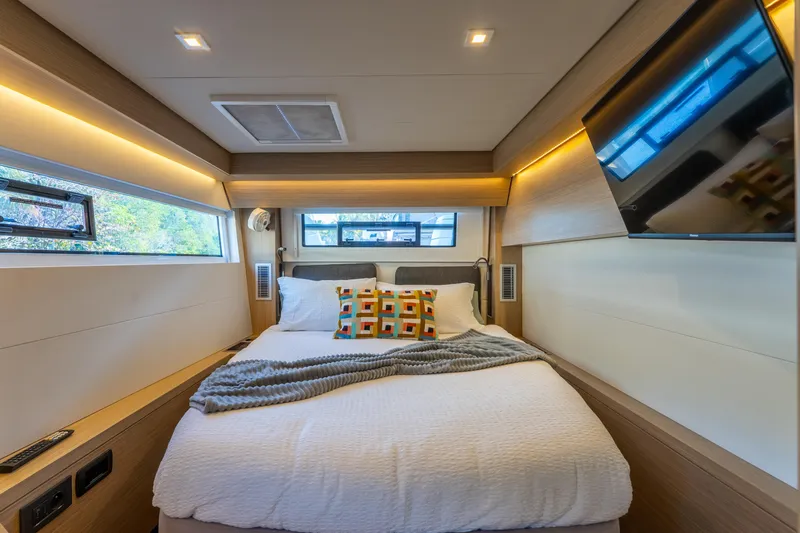 Going Deeper Yacht Photos Pics Luxurious bedroom interior of 2024 Lagoon 51 yacht with modern decor and cozy bedding.