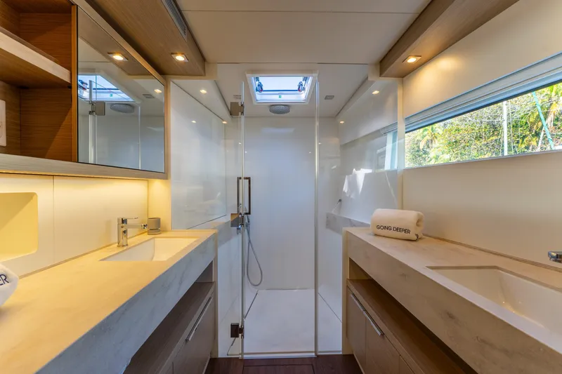 Going Deeper Yacht Photos Pics Luxurious bathroom in 2024 Lagoon 51 yacht, featuring dual sinks and modern shower.