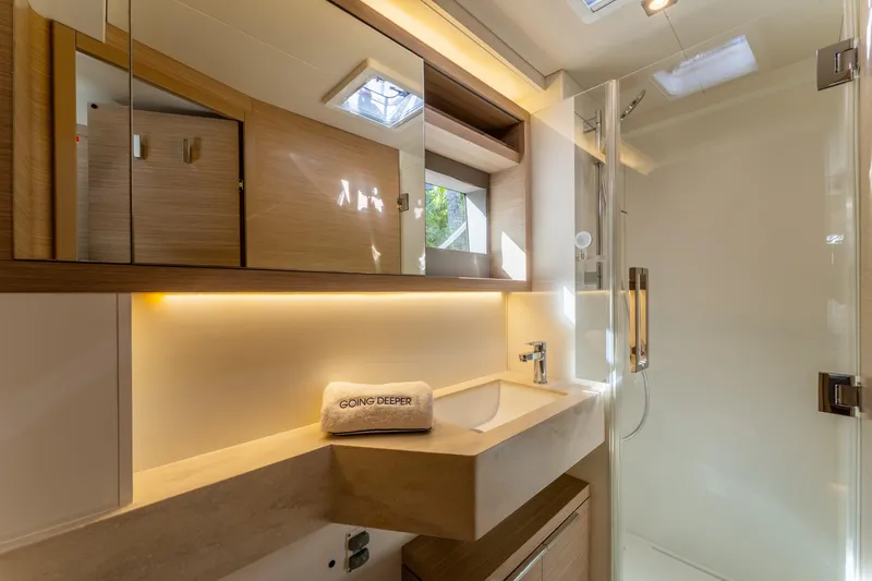 Going Deeper Yacht Photos Pics Luxurious bathroom in 2024 Lagoon 51 yacht, featuring modern fixtures and elegant lighting.