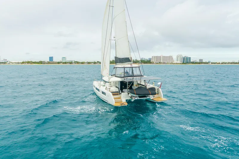 Going Deeper Yacht Photos Pics 2024 Lagoon 51 catamaran sailing near a coastal city skyline.