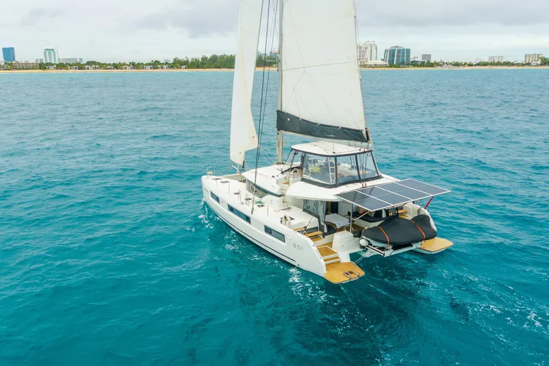 Going Deeper Yacht Photos Pics 2024 Lagoon 51 catamaran sailing on blue ocean near city skyline.