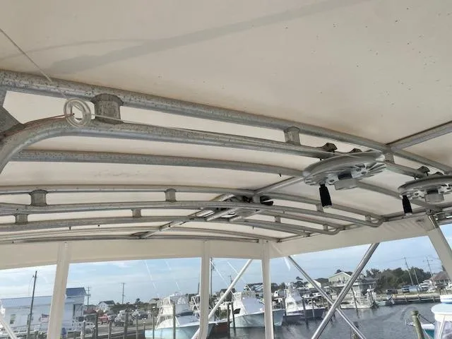 Cost Of Living Yacht Photos Pics 1985 Bertram 38 Convertible boat roof structure with marina view in background.