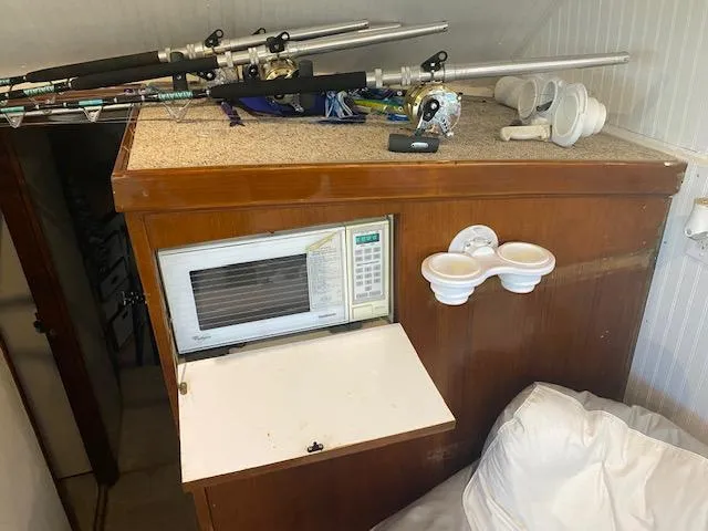 Cost Of Living Yacht Photos Pics 1985 Bertram 38 Convertible interior with fishing rods, microwave, and cup holders.