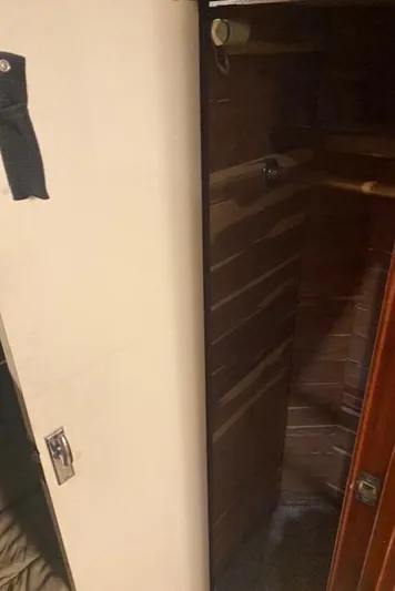 Cost Of Living Yacht Photos Pics Interior view of 1985 Bertram 38 Convertible, featuring wooden paneling and storage space.