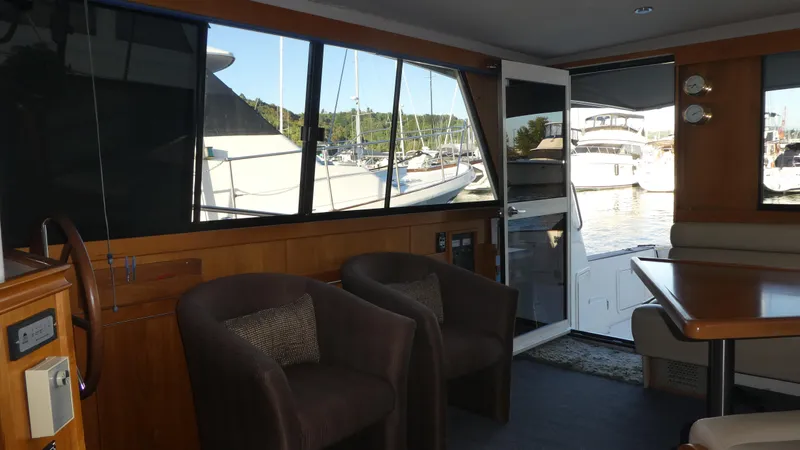  Yacht Photos Pics Interior of 1995 Riviera Convertible yacht with chairs, table, and marina view.