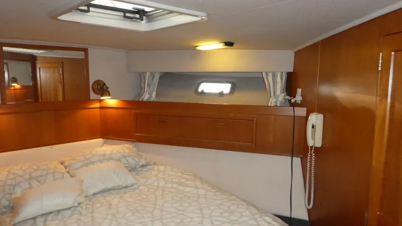  Yacht Photos Pics Cozy bedroom interior in a 1995 Riviera Convertible yacht, featuring wood paneling and soft lighting.