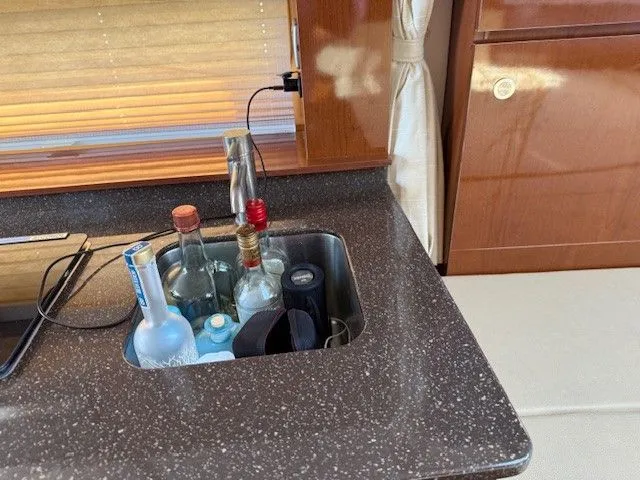 Bella Vida Yacht Photos Pics 2014 Sea Ray 310 Sundancer interior with countertop and sink, featuring assorted bottles.