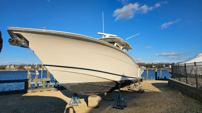  Yacht Photos Pics 2019 Scout 355 LXF boat on stands by the water, blue sky.