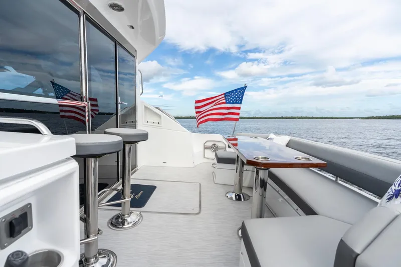 Tropical Dreamer Yacht Photos Pics 2022 Cruisers Yachts 54 Cantius deck with seating, table, and American flag.