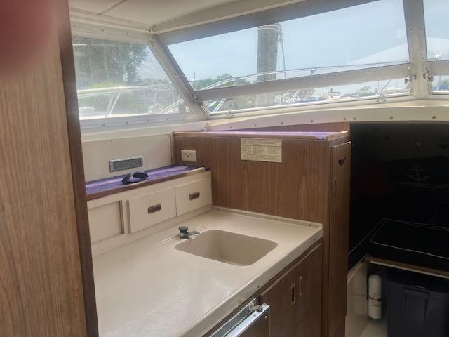 1974 Bertram 28 Flybridge interior with sink and wooden cabinetry.