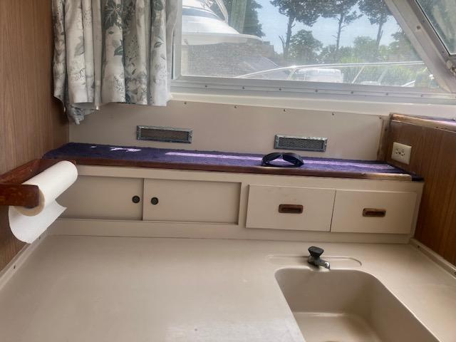 1974 Bertram 28 Flybridge interior with sink, storage, and window view.