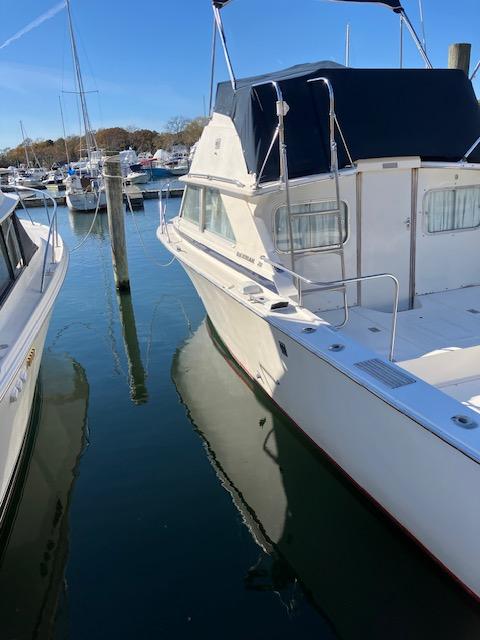 1974 Bertram 28 Flybridge boat docked in a marina, clear blue sky.