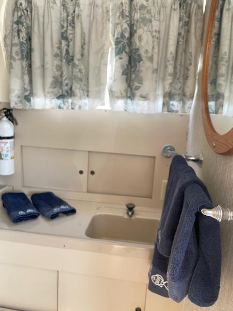 1974 Bertram 28 Flybridge bathroom with sink, mirror, blue towels, and floral curtains.