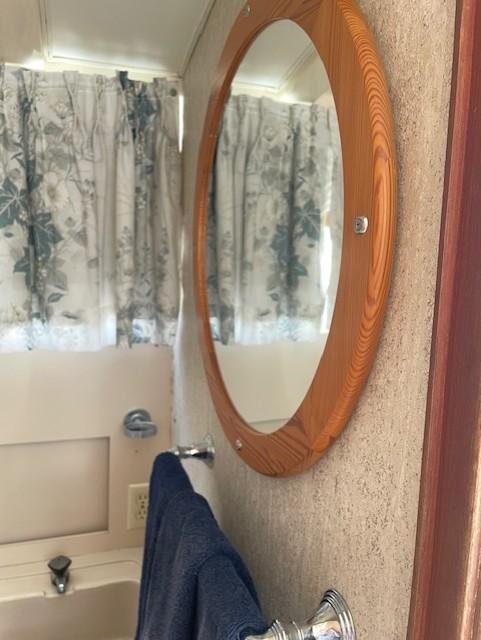 1974 Bertram 28 Flybridge bathroom with round mirror and floral curtains.