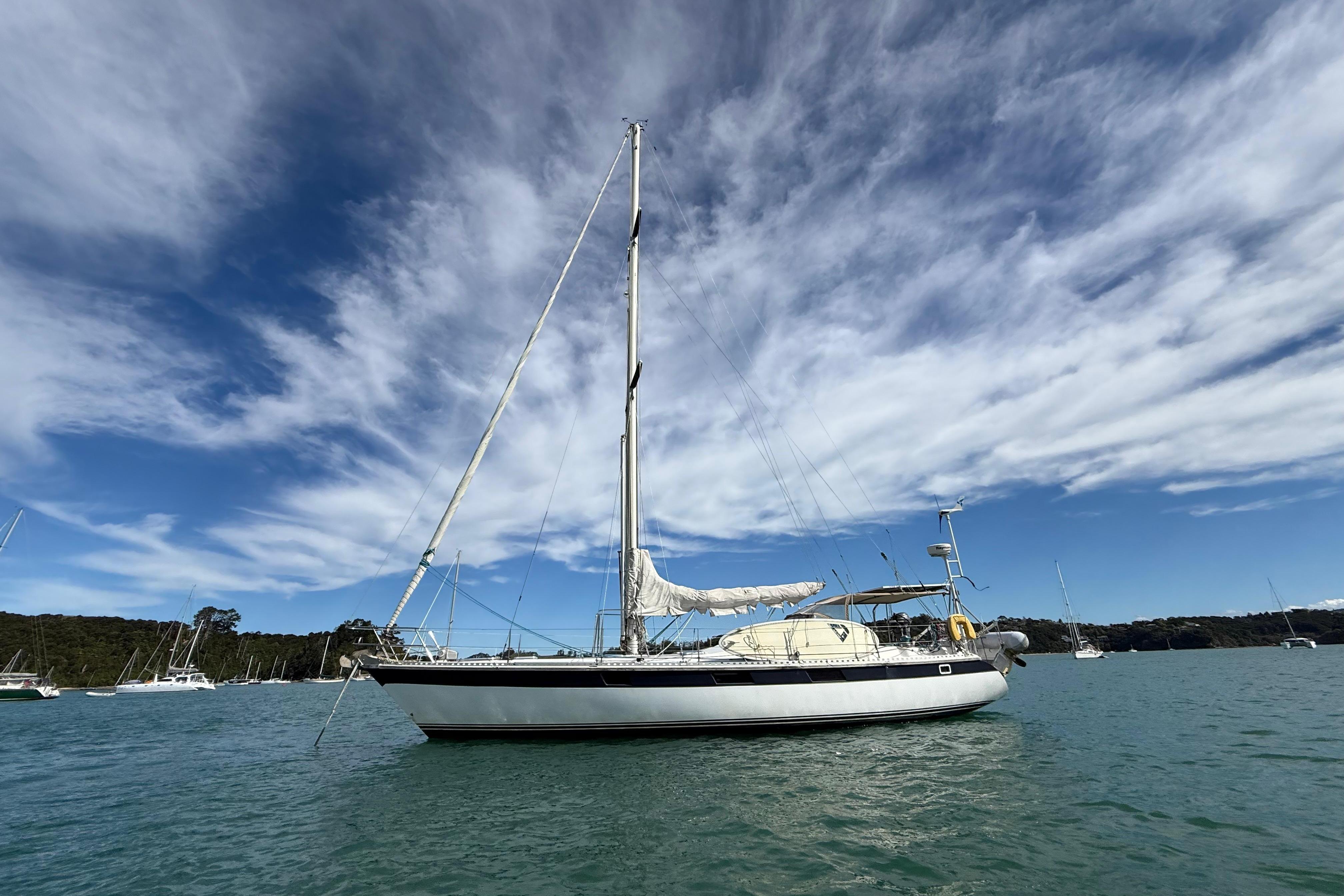 1983 Express 44 sailboat on calm water under a partly cloudy sky.