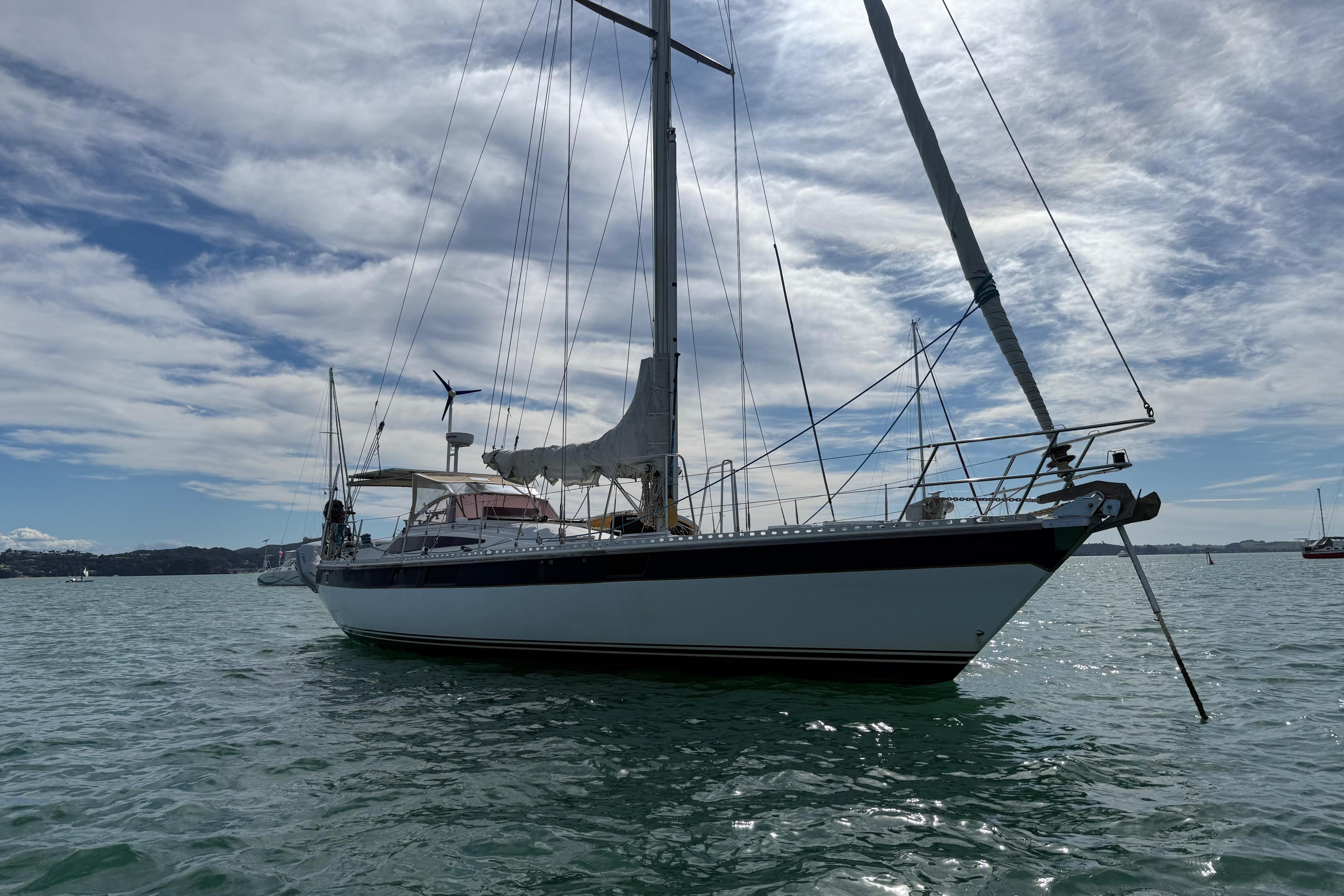 Sailboat on water, Express 44 model, 1983, under a partly cloudy sky.