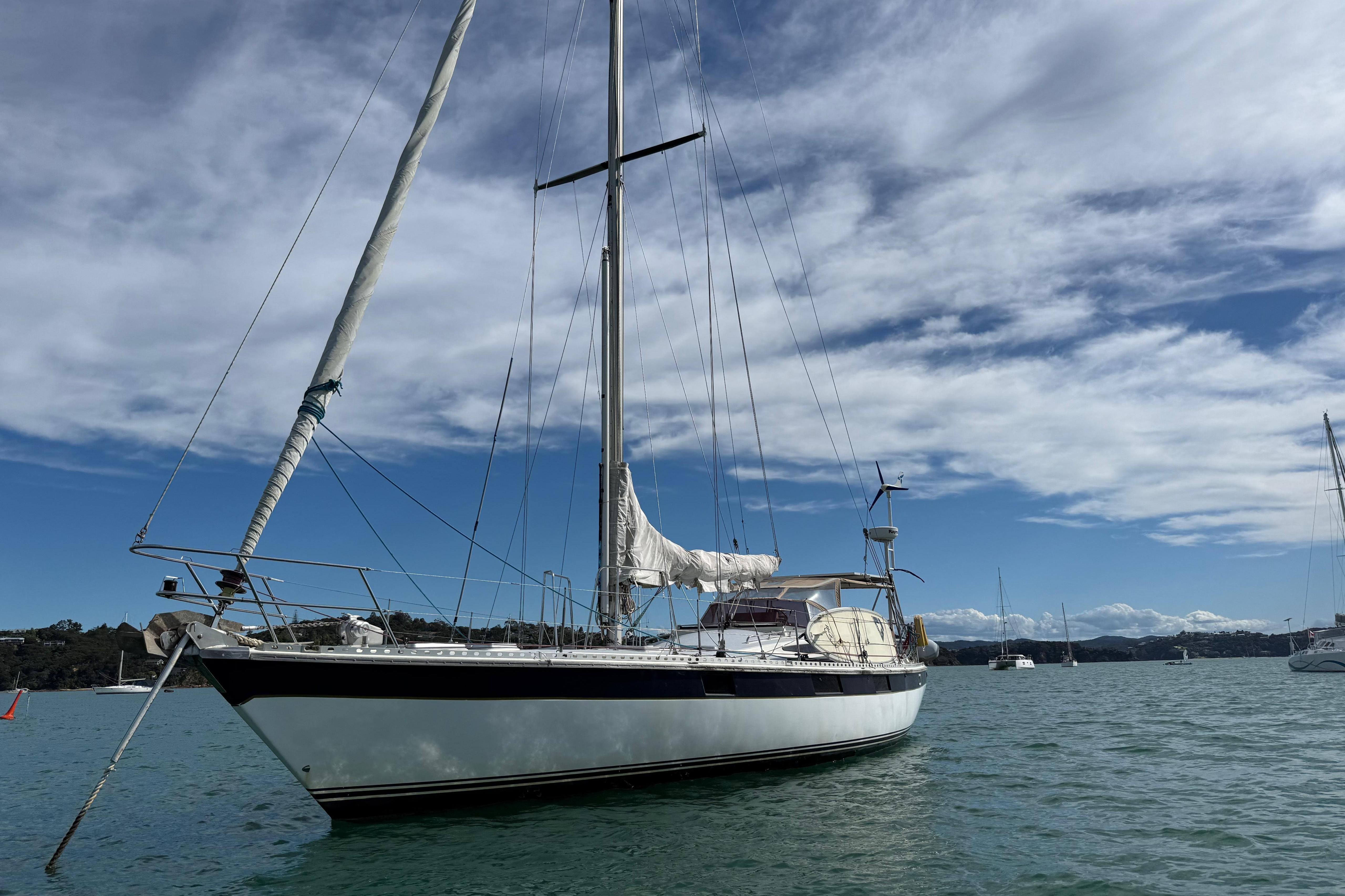 1983 Express 44 sailboat on calm water under a partly cloudy sky.