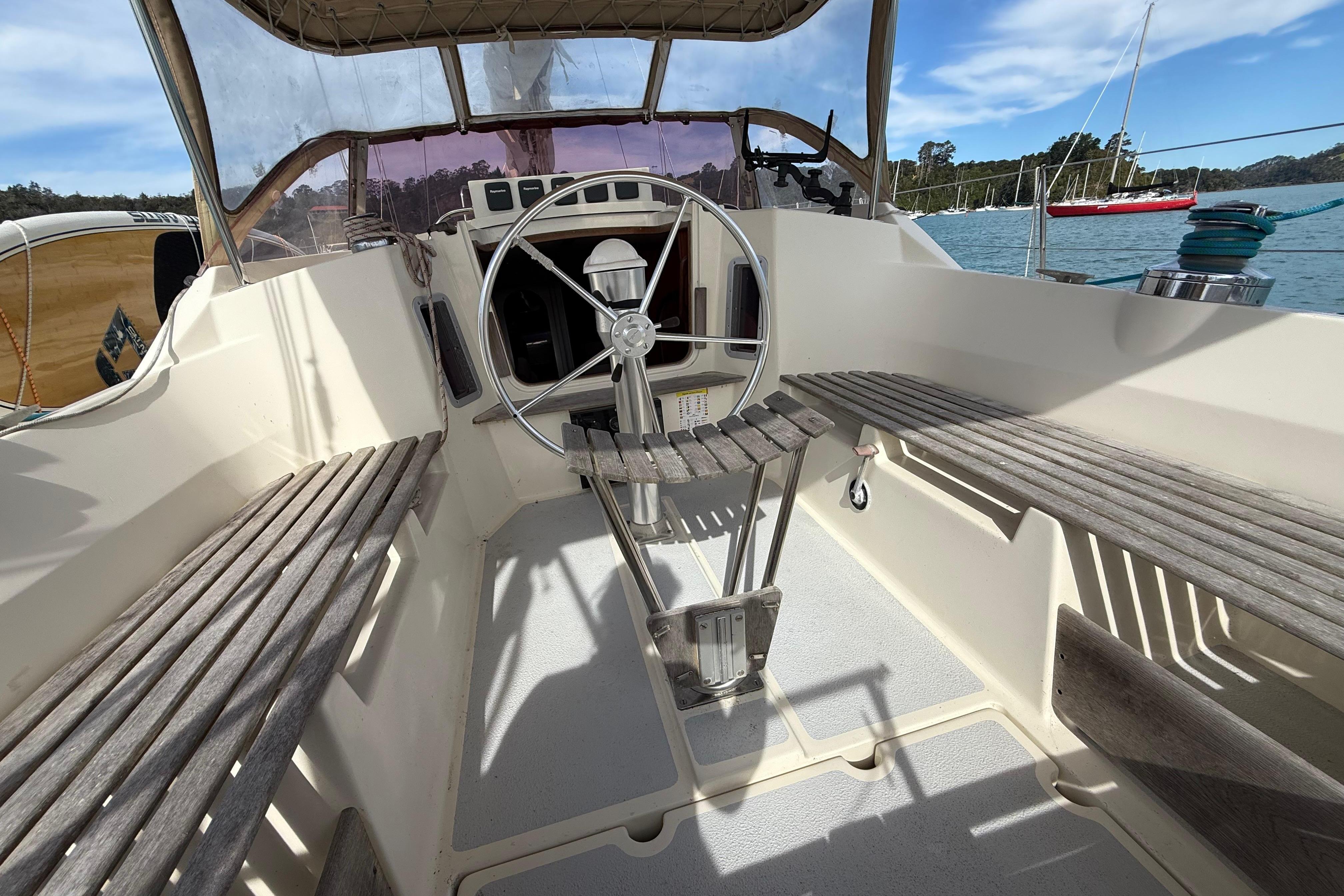 Cockpit of 1983 Express 44 sailboat with wooden benches and steering wheel.