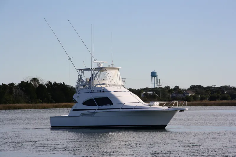 Lineage Yacht Photos Pics 2003 Bertram 390 Convertible yacht on calm water with distant trees and water tower.