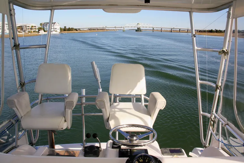 Lineage Yacht Photos Pics 2003 Bertram 390 Convertible boat interior with steering wheel and chairs on calm water.