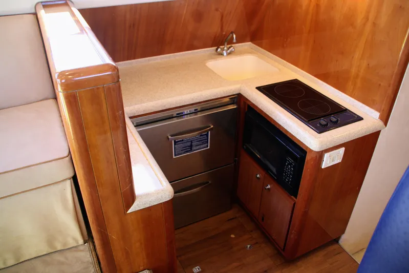 Lineage Yacht Photos Pics Compact kitchen in a 2003 Bertram 390 Convertible yacht with stove, sink, and microwave.