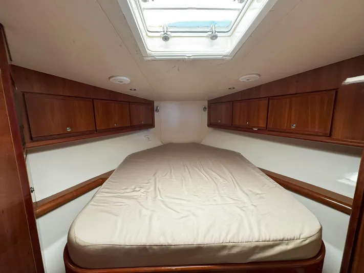 Lineage Yacht Photos Pics 2003 Bertram 390 Convertible cabin with bed, wooden cabinets, and overhead skylight.