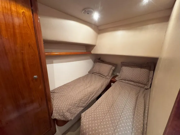 Lineage Yacht Photos Pics Twin cabin beds in 2003 Bertram 390 Convertible yacht, featuring cozy bedding and wooden accents.