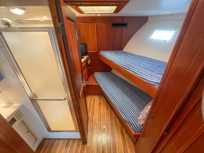 Starfire Yacht Photos Pics 1984 Hatteras 53 Motoryacht cabin with wooden interior, bunk beds, and adjacent bathroom.