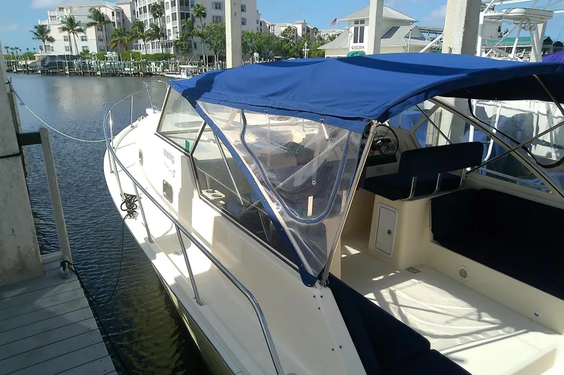 Dolce Far Niente Yacht Photos Pics 2004 Mainship 34 Pilot II docked, featuring blue canopy and spacious interior.