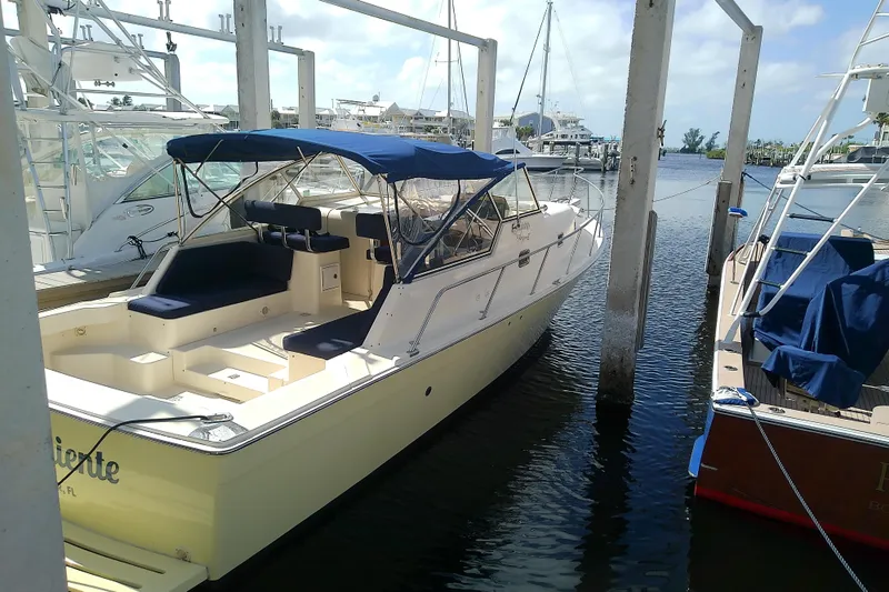 Dolce Far Niente Yacht Photos Pics 2004 Mainship 34 Pilot II docked at marina, featuring blue canopy and spacious seating.