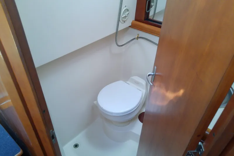 Dolce Far Niente Yacht Photos Pics 2004 Mainship 34 Pilot II boat bathroom with toilet and wooden door.