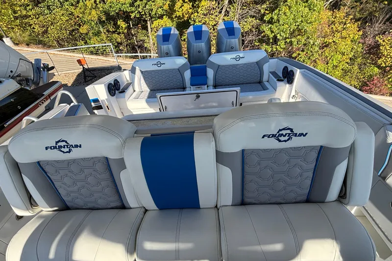  Yacht Photos Pics 2024 Fountain 38 SCX boat interior with blue and white seating, surrounded by trees.