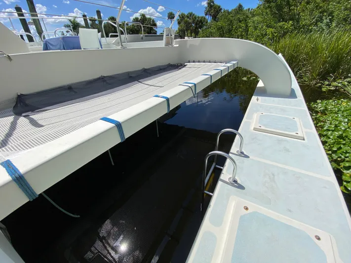 Mirage Yacht Photos Pics Catamaran deck with netting, Custom 62 model, 1996, docked near lush greenery.