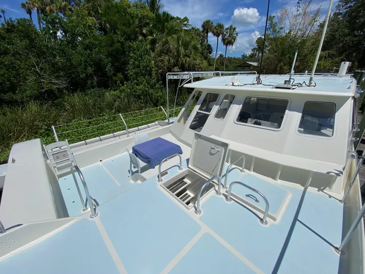 Mirage Yacht Photos Pics Custom 62 boat from 1996 with spacious deck, surrounded by lush greenery.