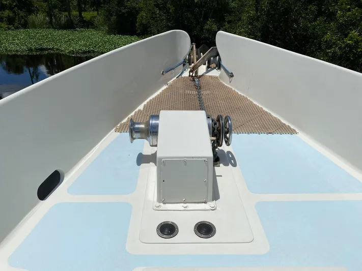 Mirage Yacht Photos Pics Bow of a 1996 Custom 62 boat with anchor winch and lush greenery.