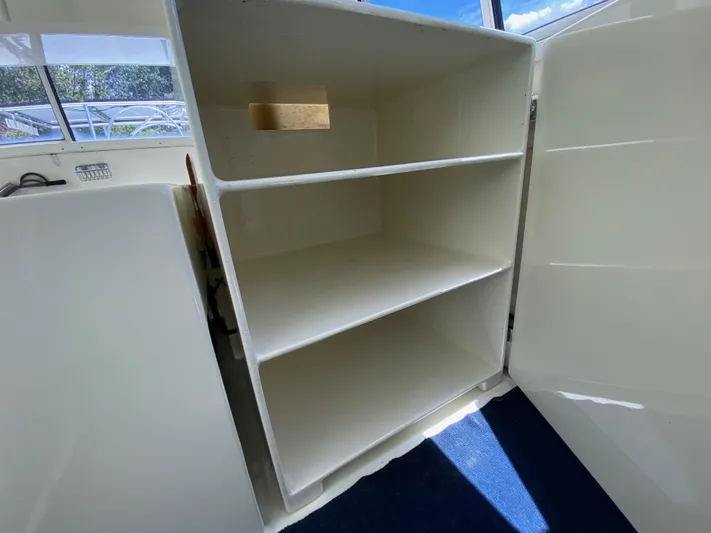 Mirage Yacht Photos Pics Open white storage cabinet with shelves on a Custom 62, 1996 model boat.