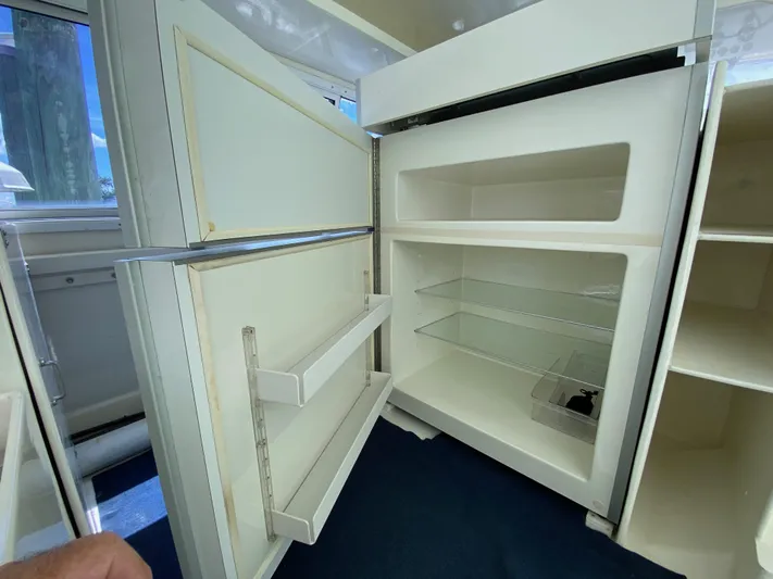 Mirage Yacht Photos Pics Open custom refrigerator, model 62, from 1996, with empty shelves and door compartments.