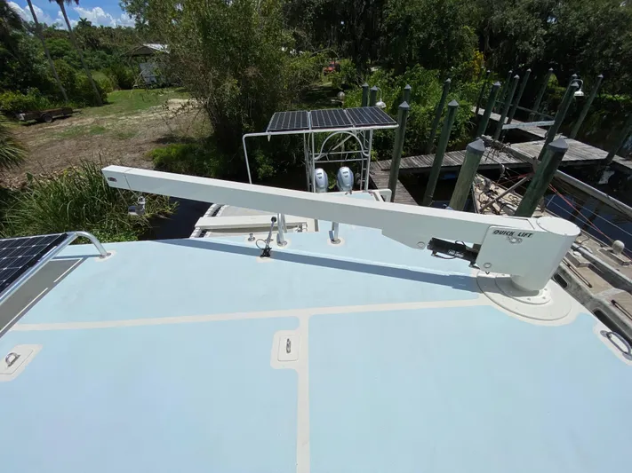 Mirage Yacht Photos Pics Boat deck with Quick Lift crane, solar panels, and lush greenery in the background.