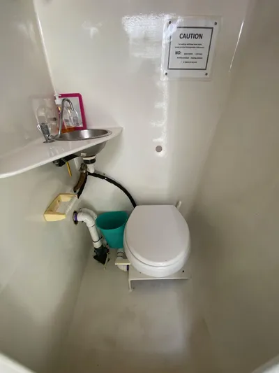 Mirage Yacht Photos Pics Compact marine bathroom with sink, toilet, and caution sign, Custom model 62, 1996.