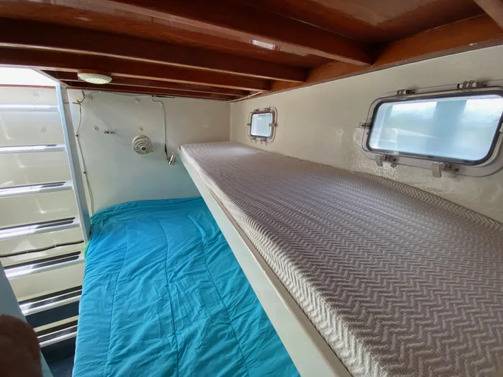 Mirage Yacht Photos Pics Small boat cabin with bunk beds, blue bedding, and wooden ceiling, Custom 62, 1996 model.