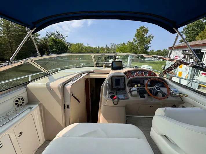  Yacht Photos Pics 2002 Sea Ray 360 Sundancer helm with navigation equipment and steering wheel, docked near greenery.