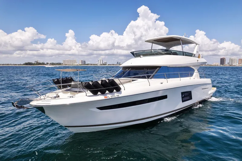 La Peque Yacht Photos Pics 2016 Prestige 620 yacht cruising on open water with city skyline in the background.