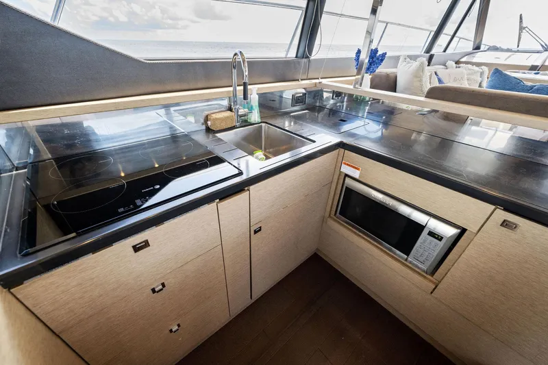 La Peque Yacht Photos Pics Modern kitchen area in a 2016 Prestige 620 yacht with sink, stove, and microwave.