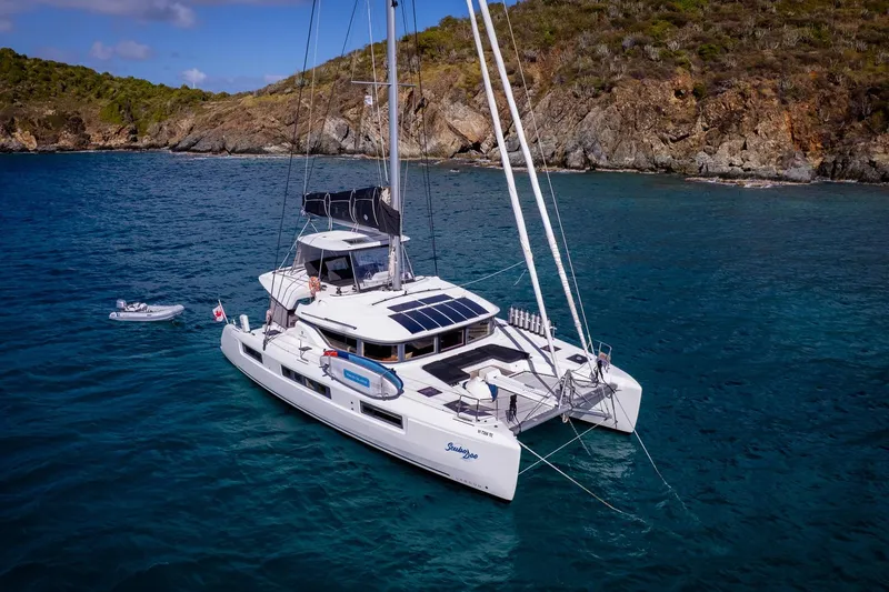 Scuba Doo Yacht Photos Pics 2021 Lagoon 50 catamaran anchored in clear blue waters near rocky coastline.